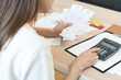 © KMPZZZ - Stressed asian young business woman, employee using calculator to calculate expenses of monthly, hand holding bills and receipt for to payment on table at home. Financial, finance of banking concept.