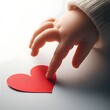 © Hajar - Close-up of a baby’s hand reaching for a red heart, symbolizing early emotional connection, love, and innocence.