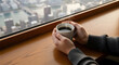 © BackgroundStudio - Hands holding a steaming coffee mug on a wooden counter overlook