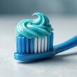 © K1drock - Close-up blue toothbrush with glossy turquoise toothpaste swirl on clean minimal background, soft light and fresh hygienic dental care concept.