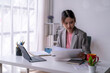 © Wasana - Young asian businesswoman working and reviewing documents at the office