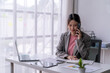 © Wasana - Asian businesswoman talking on phone and working with documents in office