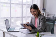 © Wasana - Asian businesswoman working with digital tablet and stylus pen in modern office