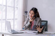 © Wasana - Businesswoman talking on phone and using digital tablet in office