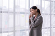 © Wasana - Businesswoman laughing while talking on phone near window