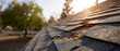 © Jhati - A close-up view of a damaged roof with missing shingles and worn-out roofing material in the sun