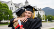 © Rashed - Two young women are embracing, dressed in graduation gowns and caps