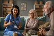 © Goran - Senior couple looking at medical records on digital tablet during a visit by the doctor at home.