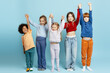 © Maria Vitkovska - Diverse excited children standing together with raised hands on a blue background