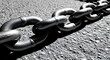 © ASIF KARIM - Closeup of large metal chain lying on rough asphalt surface