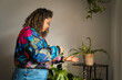 © lorenzophotoprojects - Brazilian woman watering houseplant for plant care hobby