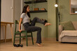 © sutulastock - Athletic woman performing seated core exercise on chair at home using bodyweight training to improve balance stability and lower body strength during indoor fitness workout