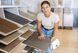 © JackF - Young woman buyer chooses sample of laminate flooring in hardware store
