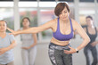 © JackF - Positive middle aged woman, participating in beginner ballet class, practicing basic movements with female group of various ages in bright choreography studio with natural lighting