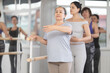 © JackF - Positive senior female citizen enjoying learning basics of ballet, practicing first position at barre in relaxed, friendly class environment with group of women in mirrored studio..
