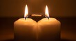 © Suryani - Two lit white candles connected by a burning wick, symbolizing connection and shared moments in warm light
