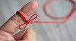 © Suryani - Close-up of a hand with a red string tied around a finger as a reminder or memory aid