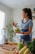 © crizzystudio - Woman smiling while preparing fresh healthy salad