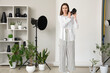 © Pixel-Shot - Female photographer with camera and houseplants in photo studio