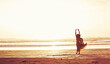 © JamDay/peopleimages.com - Woman, sunset and beach with freedom for travel, holiday or weekend vacation in nature. Female person, back view or hands in air with space or waves for outdoor getaway or trip on ocean coast by sea