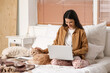 © Pixel-Shot - Pretty young woman with laptop and cute Maine Coon cat sitting on bed at home