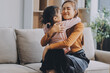 © ARMMY PICCA - A cheerful Asian mother helps her young daughter do homework and color a book at home, while the father works on a laptop in the background. A cozy, bright, and modern family lifestyle.