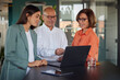 © Westend61 - Businessman using laptop near colleagues at office