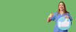 © Pixel-Shot - Beautiful young female nurse with like icon showing thumb-up gesture on green background