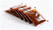 © Yapi - A row of plastic condiment sachets filled with brown savory sauce or soy sauce. Liquid seasoning packaging for fast food and takeaway isolated on white background.