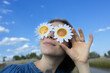 © Anna - beautiful teenage girl wearing daisy-shaped glasses against sky background. Her eyes are closed, she's enjoying the moment. sweet young woman relaxes and dreams in a park. Walking in spring or summer