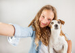 © Tatyana Gladskih - Smiling teen with dog making selfie photo on smartphone over white background  cute girl