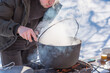 © T.Den_Team - Outdoor winter cooking, man preparing food in cauldron
