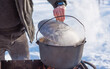 © T.Den_Team - Outdoor winter cooking, man preparing food in cauldron