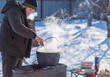 © T.Den_Team - Outdoor winter cooking, man preparing food in cauldron
