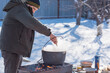 © T.Den_Team - Outdoor winter cooking, man preparing food in cauldron