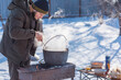 © T.Den_Team - Outdoor winter cooking, man preparing food in cauldron