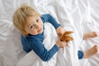 © Tomsickova - Cute child, lying in bed, playing with little stuff toy