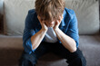 © mizina - Young man (zoomer) sitting and holding his head in stress, burnout and mental exhaustion.