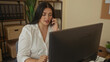 © Krakenimages.com - Woman working at office desk on phone with computer in a professional setting, showcasing a young plus size woman in business environment.