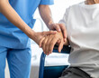 © magele-picture - Pflegekraft hält die Hand eines älteren Patienten im Rollstuhl