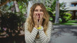 © Krakenimages.com - Woman face shock outdoors provides striking moment as blonde young individual holds hands near mouth while wide eyes reveal surprised expression.