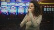 © Krakenimages.com - Woman holding hand to mouth and hand to chest at slot machines inside a casino building, eyes closed coughing; anxiety loss.
