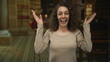 © Krakenimages.com - Woman raises both hands above her head in church building, smiling with open mouth and laughing while facing camera; joy celebration.