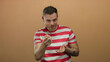 © Krakenimages.com - Young man with a tattoo in a striped shirt gesturing in front of a plain brown background suggesting communication and expression