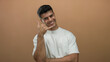 © Krakenimages.com - Young man smiling confidently in casual attire against a soft brown background, exuding charm and friendliness in an isolated portrait setting.