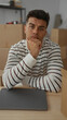 © Krakenimages.com - Young man relaxes in new home sitting at table in modern living room surrounded by packing boxes with laptop nearby suggesting a fresh start