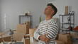 © Krakenimages.com - Young man standing with arms crossed in a new home living room surrounded by boxes and decor, creating a vibrant atmosphere.