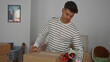 © Krakenimages.com - Young man packing boxes in a living room of a new home, preparing for a move with cardboard boxes and tape.