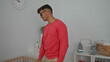 © Krakenimages.com - Man in bedroom with baby crib wearing casual outfit indoors, hand resting on furniture, soft decor visible, pink sweater contrasting with light room ambiance.