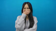 © Krakenimages.com - Young chinese woman laughing with hand on face against isolated blue background wall offers a joyful and candid moment.